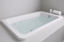 Badewanne mit Wasser gefüllt in Bad mit grauen Fliesen